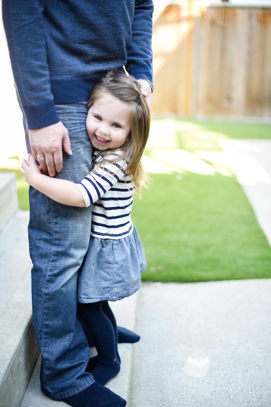 A little girl hugs a parents legs for our Kindergarten Prep article.