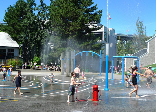 Spray park in Metro Vancouver called Granville Island, kids running around enjoying the spray park on a hot summer day
