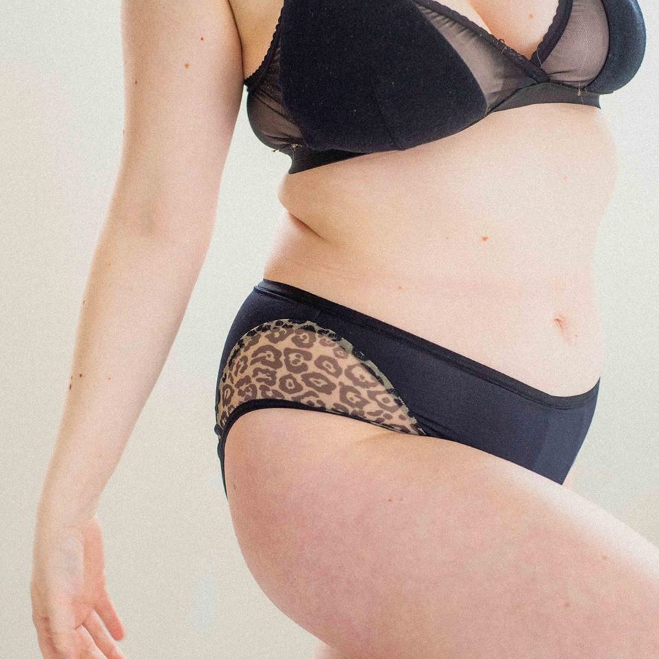 A picture of a woman's torso and arm. She is wear a black bra and matching black panties.