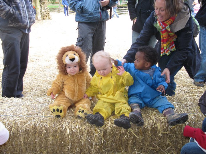 Three children in costumes on a hay stack