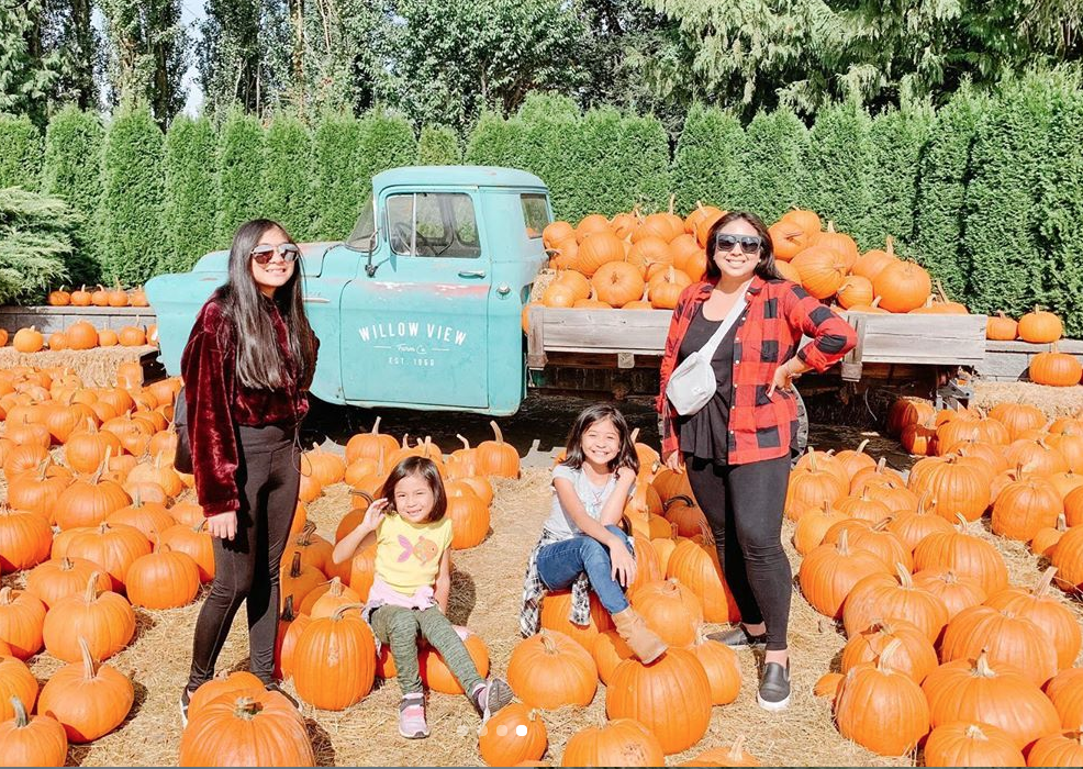 Family at Willow View Farms posing with pumpkins in front of a decorative truck full of pumpkins