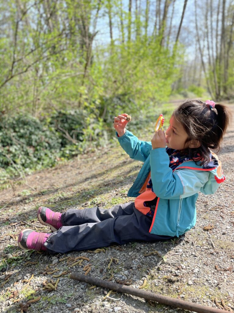 Vancouver Outdoor School. Child looking through a magnifying glass.