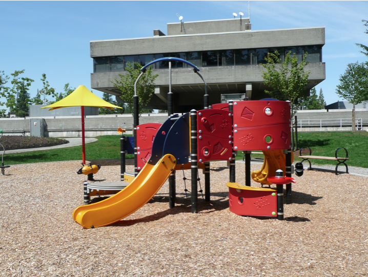 A playground red, blue, and yellow structor with three slides and various climbing fixtures.