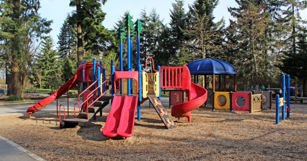 A playground red, blue, and yellow structor with three slides and various climbing fixtures.