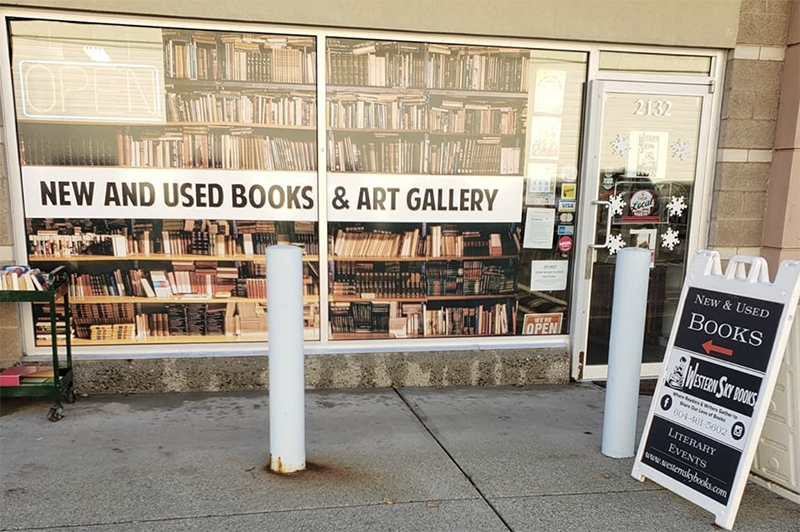 An outside photo of a bookshop window, the glass windows read new and used books.