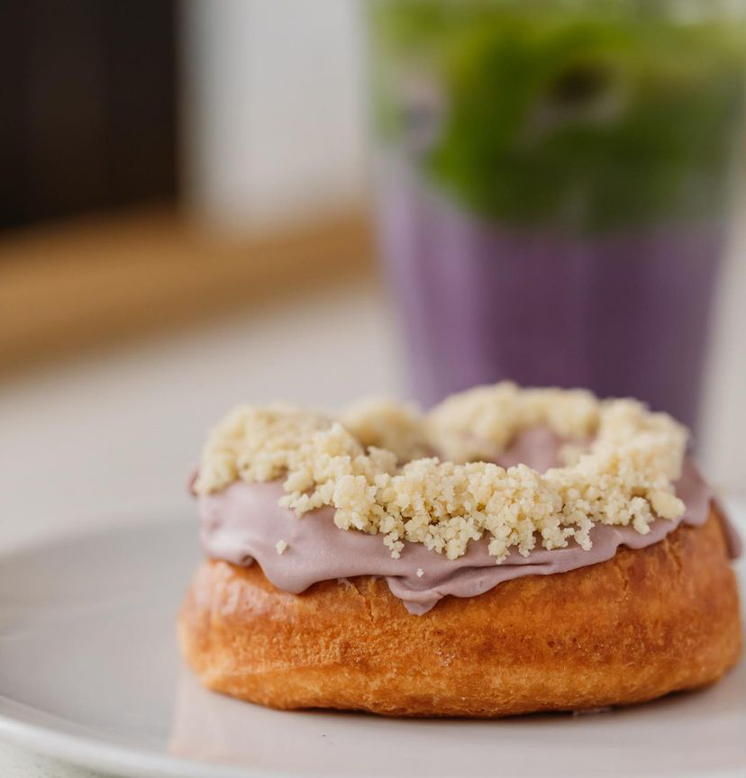 A close up os a donut with purple icing and white crumbs on the top.