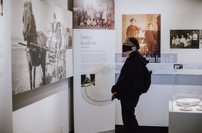 A woman stands in front of an exhibit with her hands crossed in front of her.
