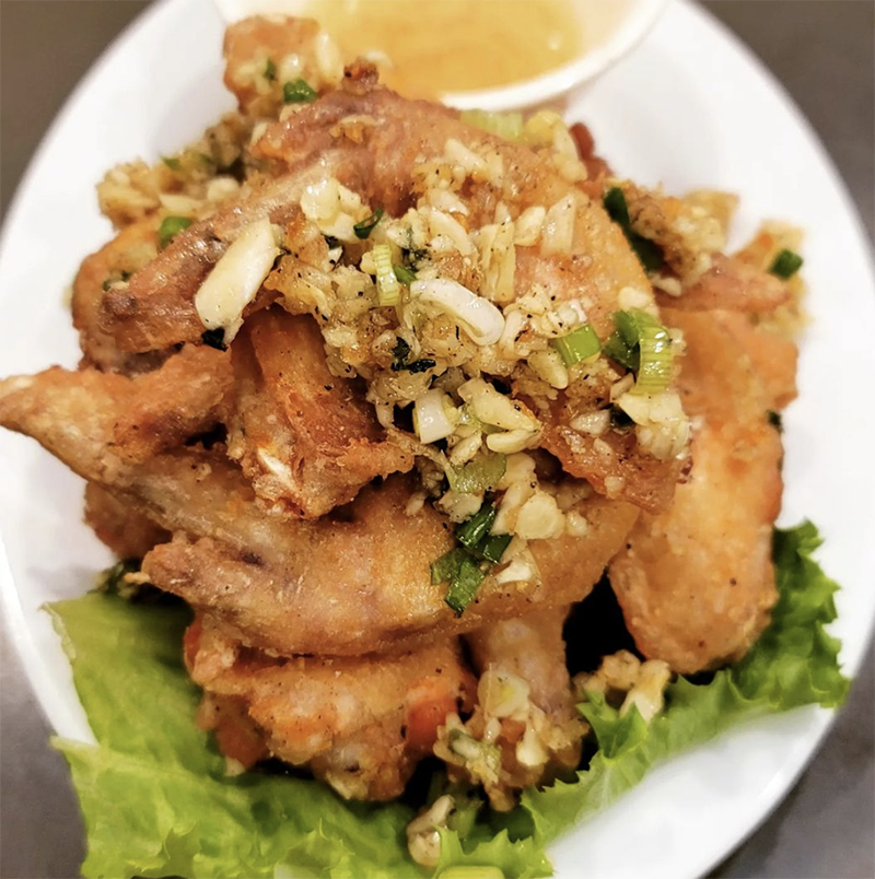 A close up deep friend chicken wings topped with chives from China Town in Vancouver.