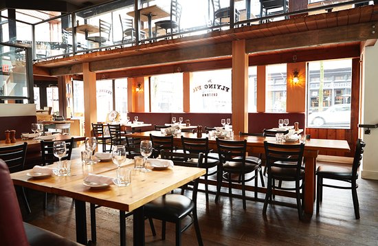 A photo of a two story open space with lots of light and wooden chairs and tables. A beautiful open space restaurant in Vancouver perfect for big parties.
