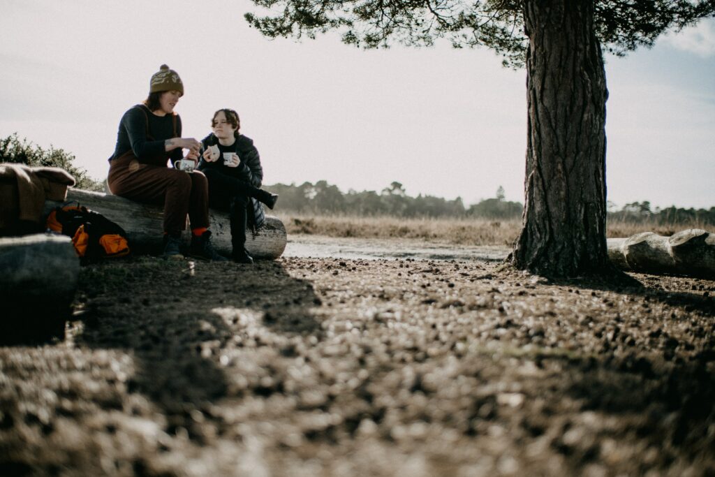 A mom and teen share a picnic on a log.