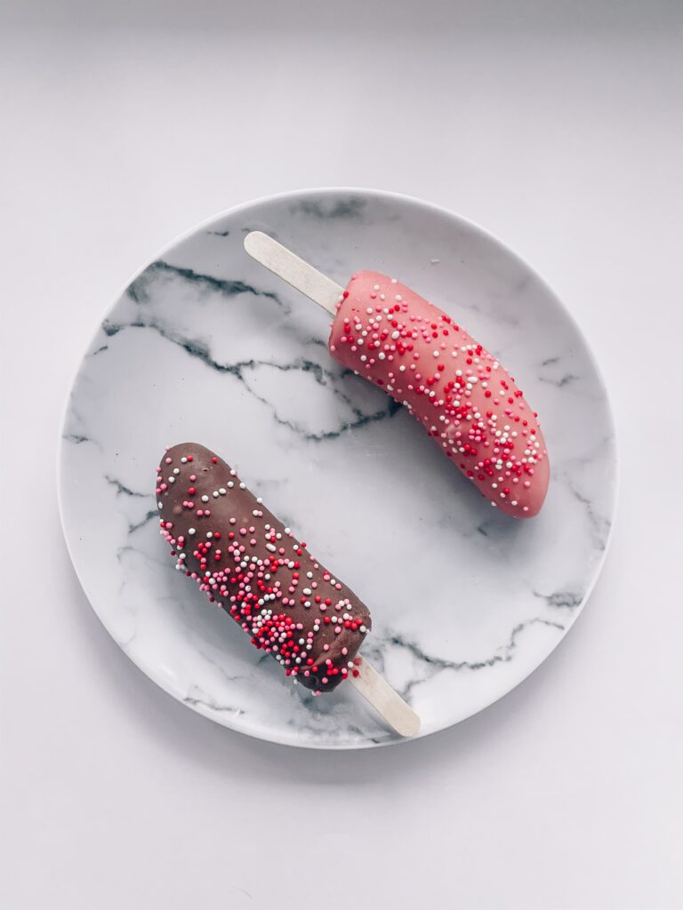 Two frozen bananas dipped in chocolate with sprinkles for pro heatwave tips.