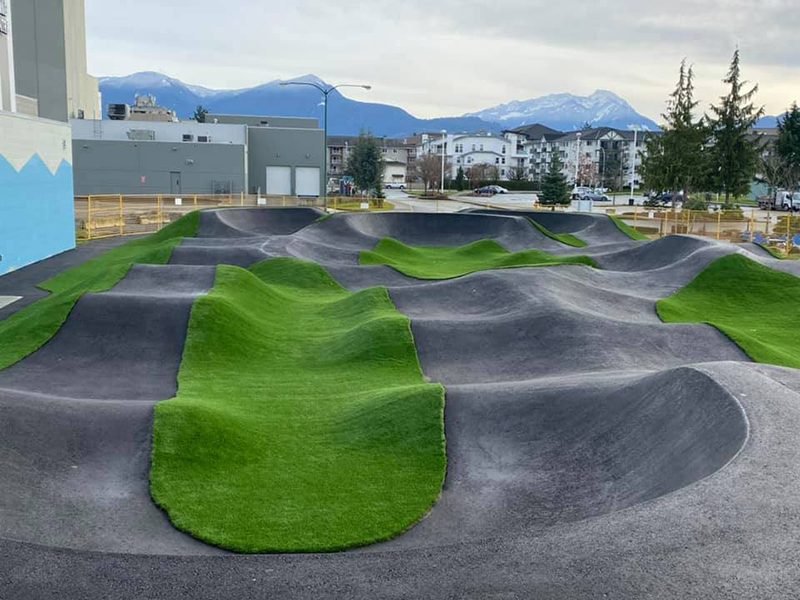 A panoramic view of an asphalt bike track with green patches of turf around.