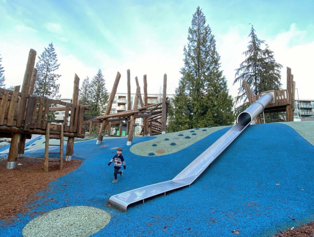A big playground called Moodyville Playground in North Vancouver, There is a little boy walking on the playground area. Something to do for May Long Weekend.
