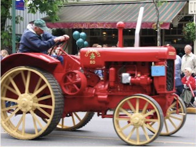 A man on a red vintage tractor for the May Day Parade held in Fort Langley for the Victoria Day Long Weekend