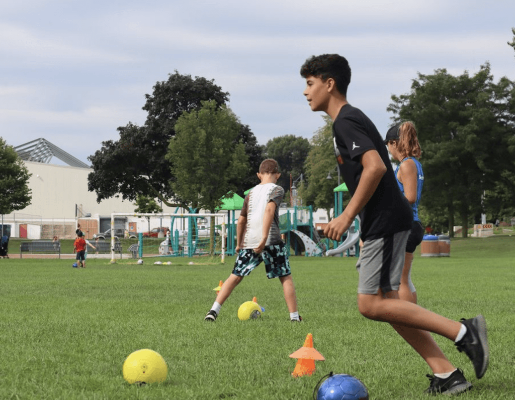 a Kid in a black shirt kicking a soccer ball