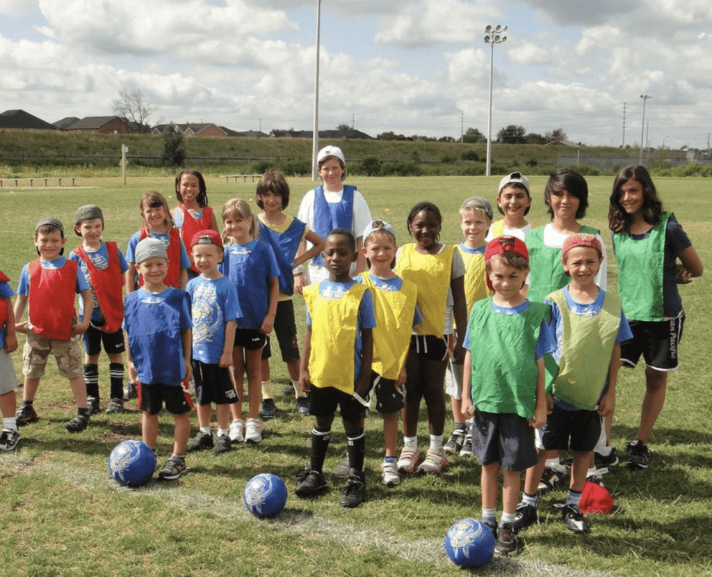 A group of kids in different color jerseys getting ready to play soccer