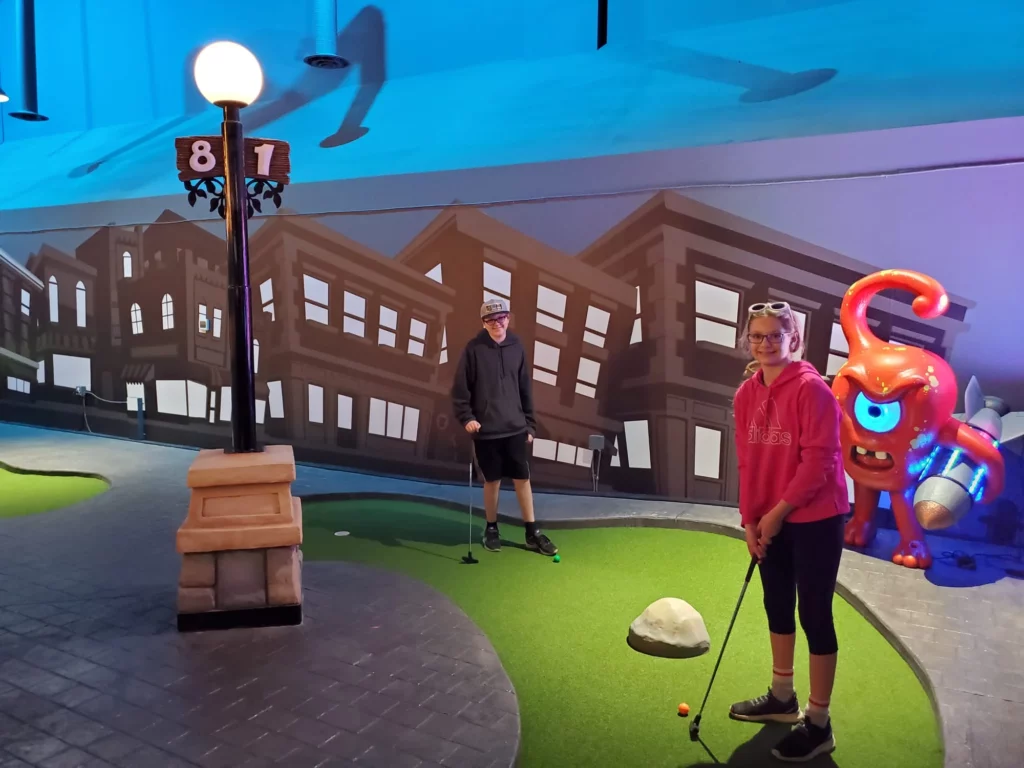 A boy and girl at the mini golf in Central City Park. Neat murals and bright colors