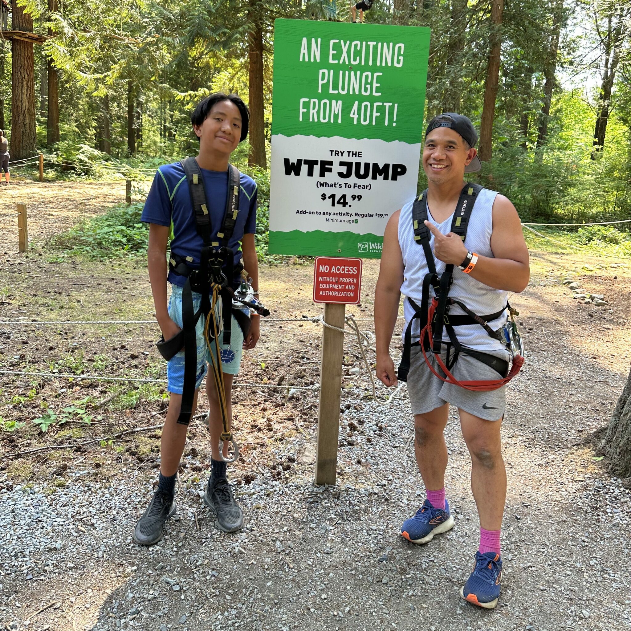 a father and son standing by the WTF Jump sign to get ready to jump 40 feet from the tree