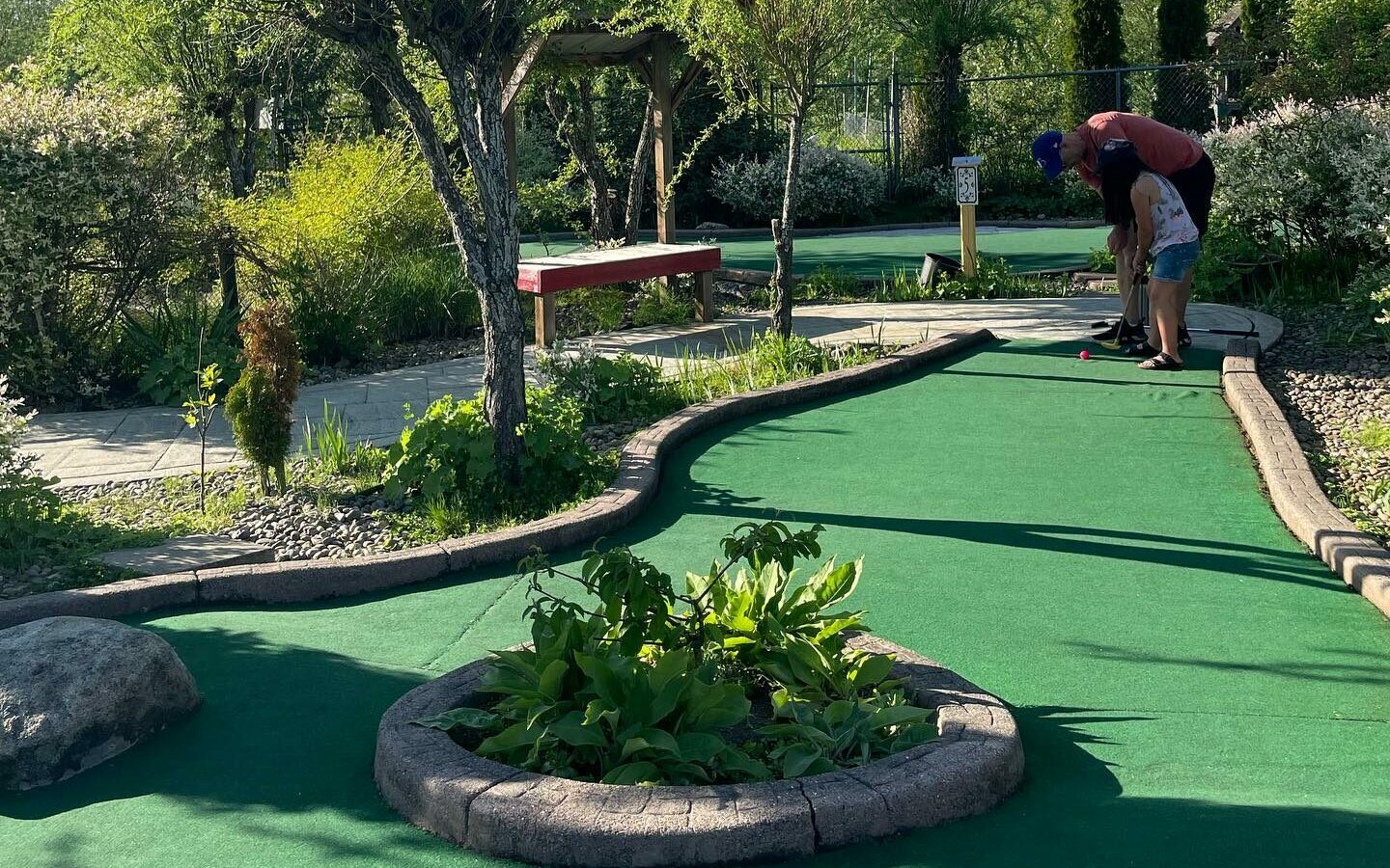 A father and his daughter putting at the Hi-Knoll mini golf course