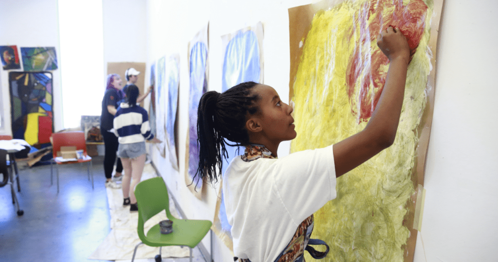 A young teenage girl painting artwork at the studio