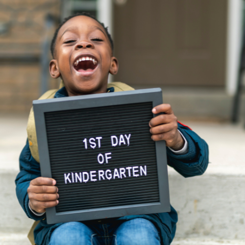 little boy smiling holding a sign 1st day of kindergarten
