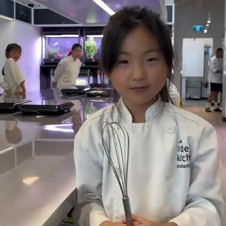 A girl holding a whisk while at her cooking class