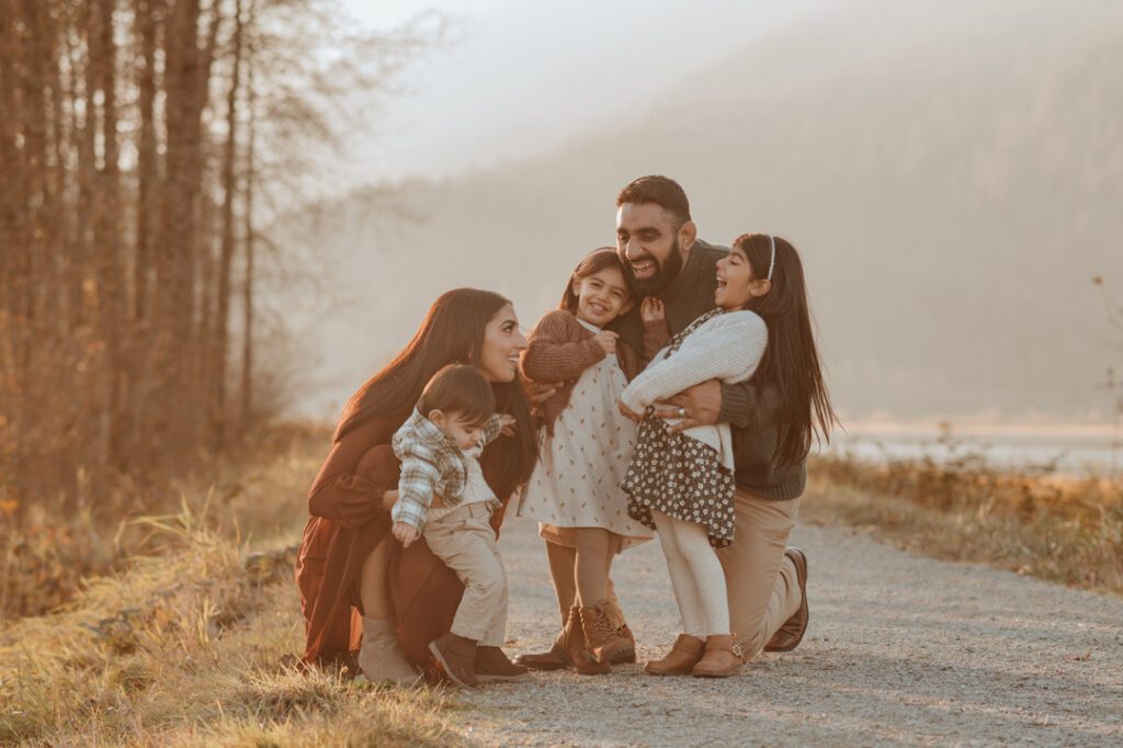 A family of 5 taking a fall photoshoot in a field by the mountains done by a top Vancouver Family photographer