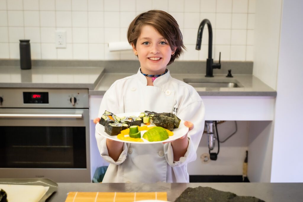 A cooking student so proud of what she made in the Little Kitchen Academy cooking class