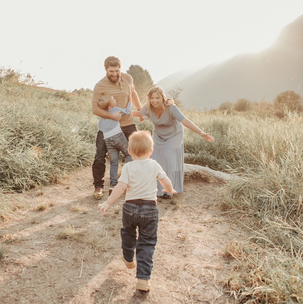A family of 4 taking a family photoshoot in a field by the mountains by one of the top Vancouver Family photographers