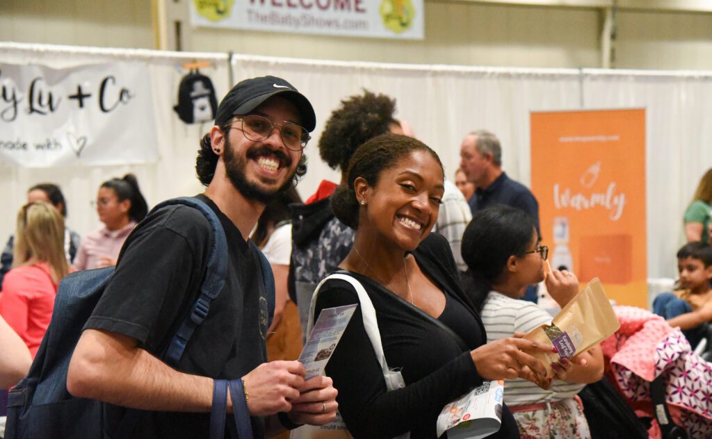 A couple smiling with samples they received at the baby show in Vancouver