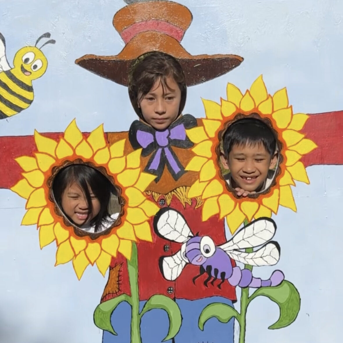 3 kids taking a picture in a painted mural scarescrow for a halloween event in Metro Vancouver