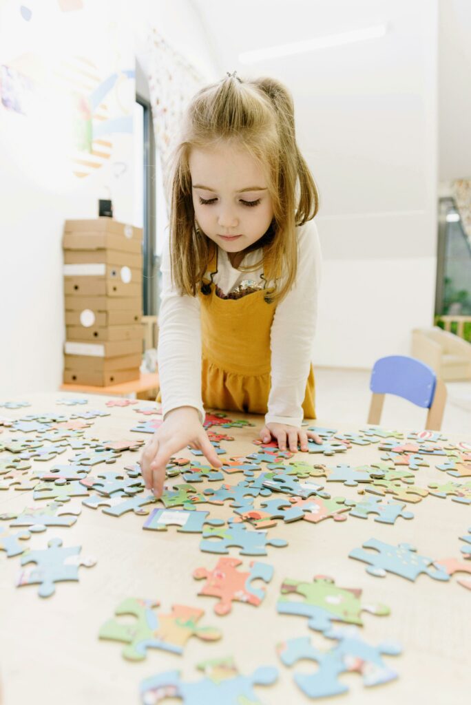 Little girl playing puzzle on a table as an indoor activity for snow days
