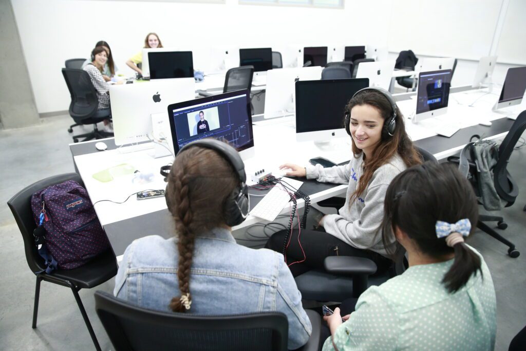 A group of students in front of the computer discussing about the video they are producing at the Emily Carr University Summer Camps