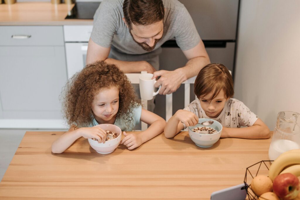 A dad and his 2 kids a girl and boy eating breakfast at the table