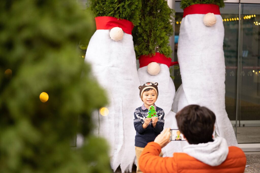 A little boy smiling holding a christmas cookie taking a picture in front of the Vancouver Aquarium for the Holiday Splash Event