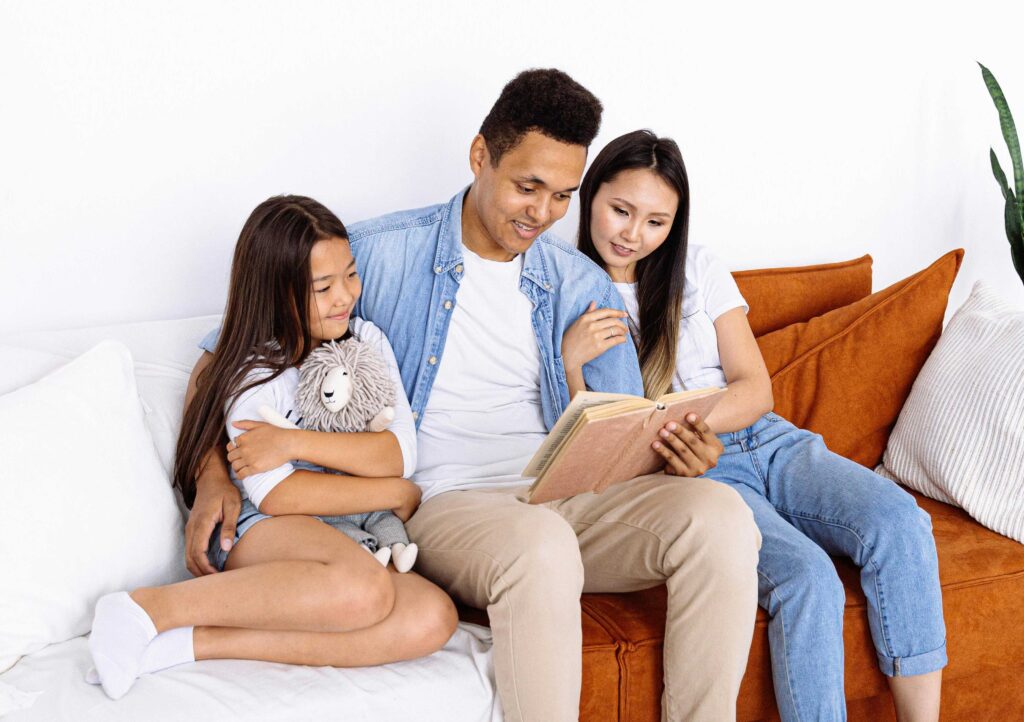 Family sitting together on the couch reading a book during daylight savings day