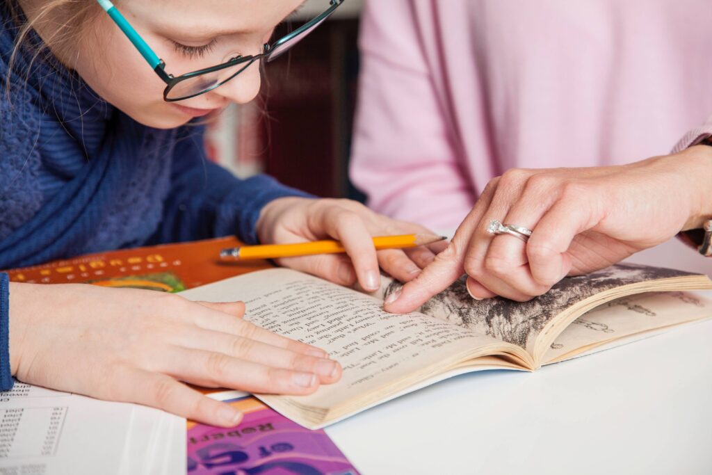 A girl reading through the book with a tutor and breaking down what each sentence means that shows signs of a struggling reader