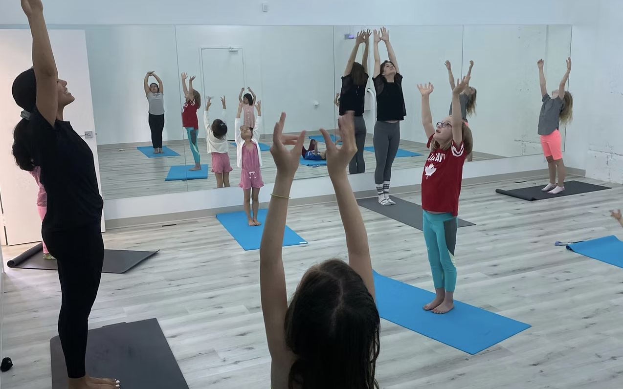 This is at the Uphoria Yoga Studio with kids doing yoga moves and Tara Shayegan leading the class.