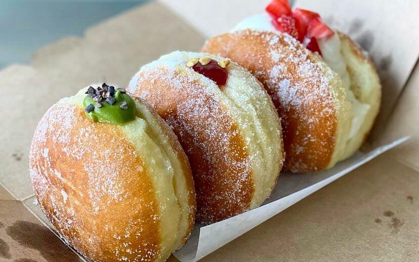 Three filled donuts sit on an open box.