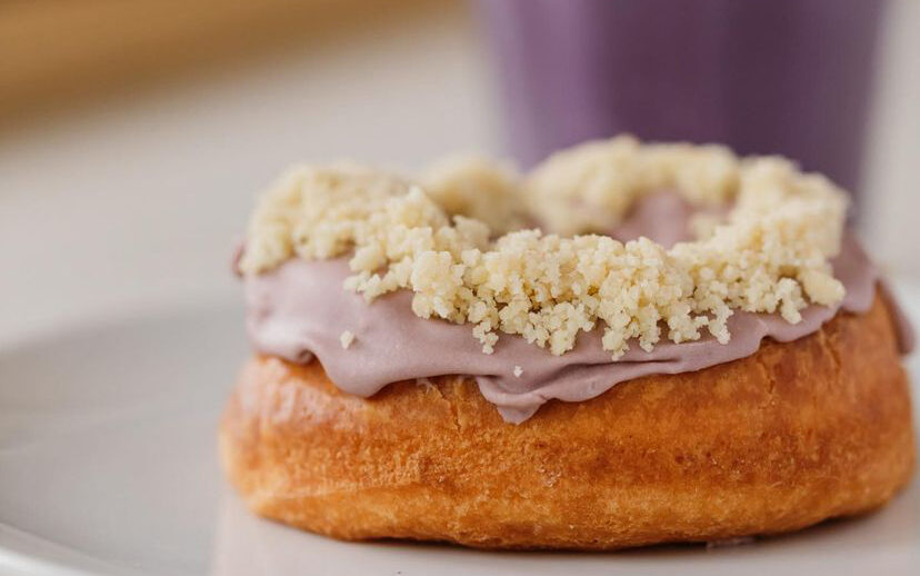 A close up os a donut with purple icing and white crumbs on the top.